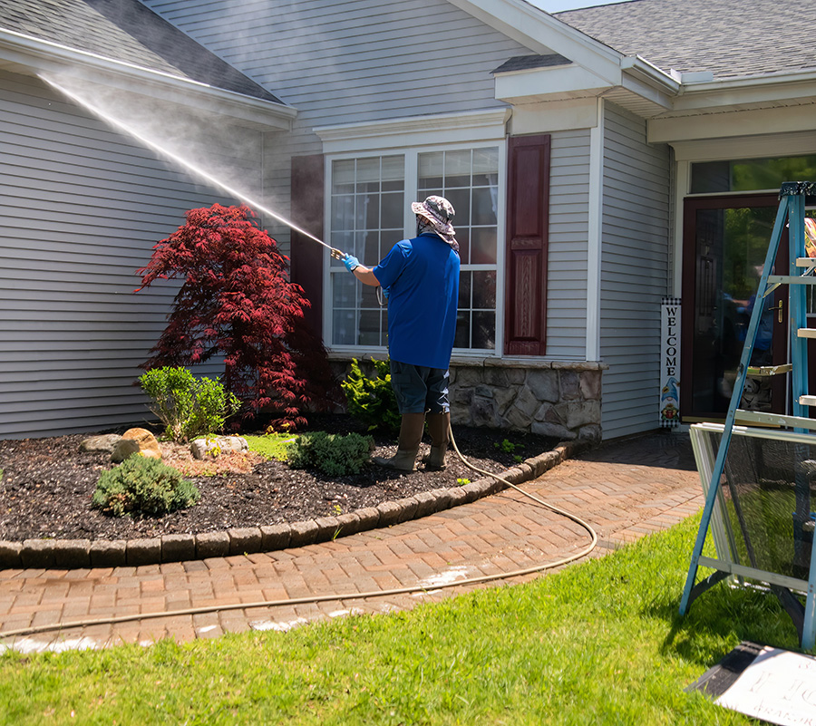 man pressure washing a home